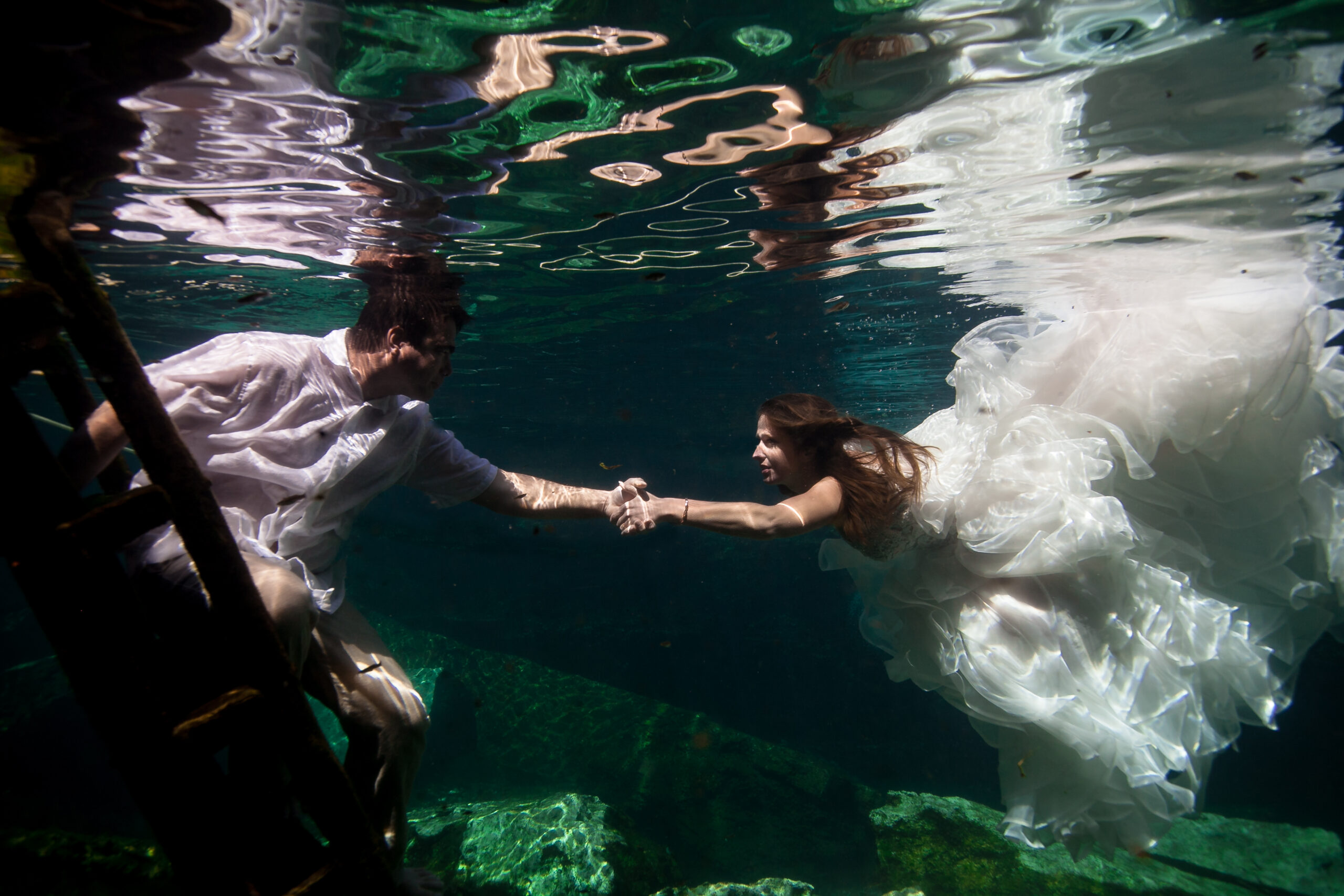 newlyweds swim to each other underwater in cenote