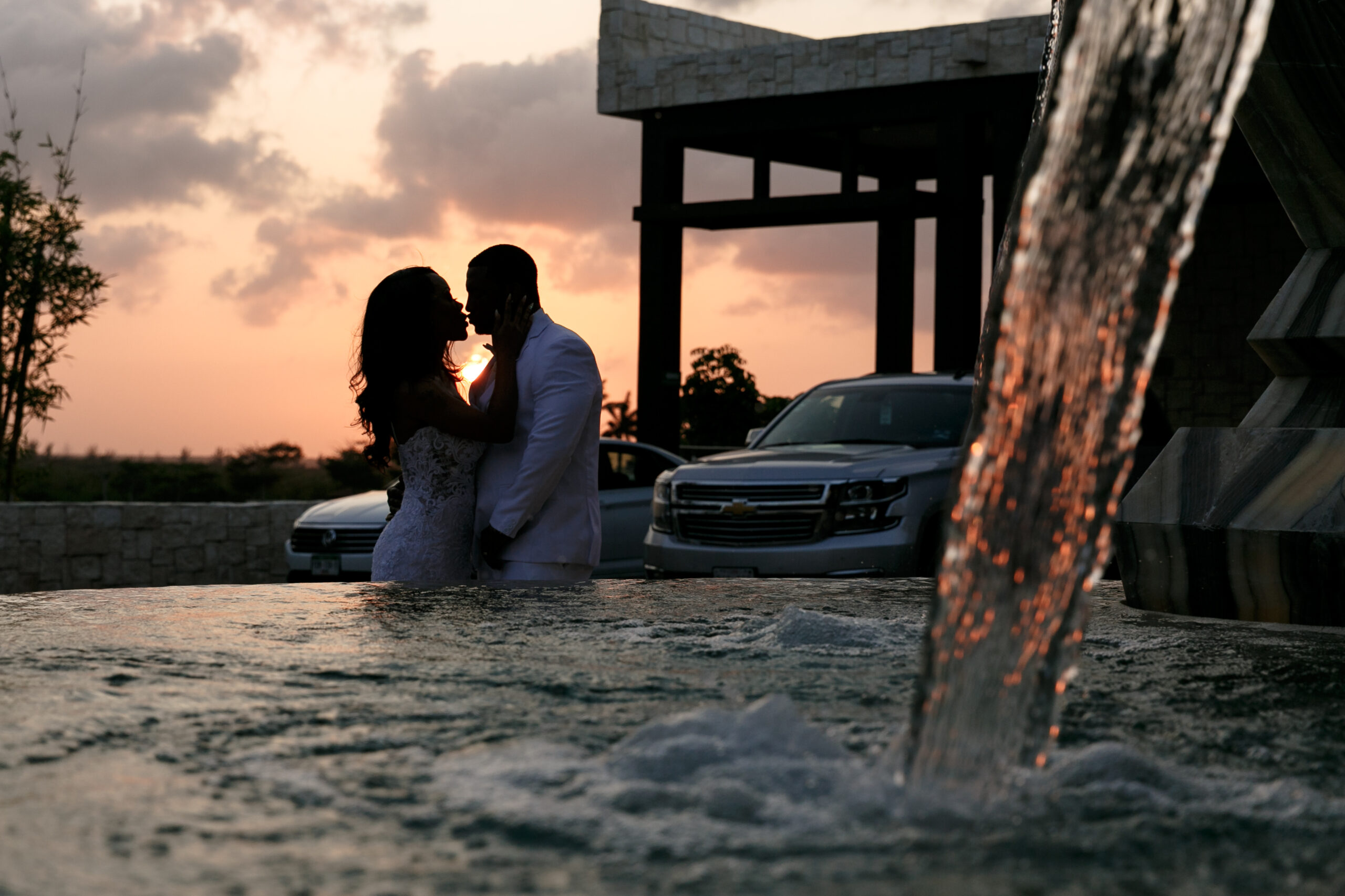 Newlyweds silhouetted in gold of dramatic sunset