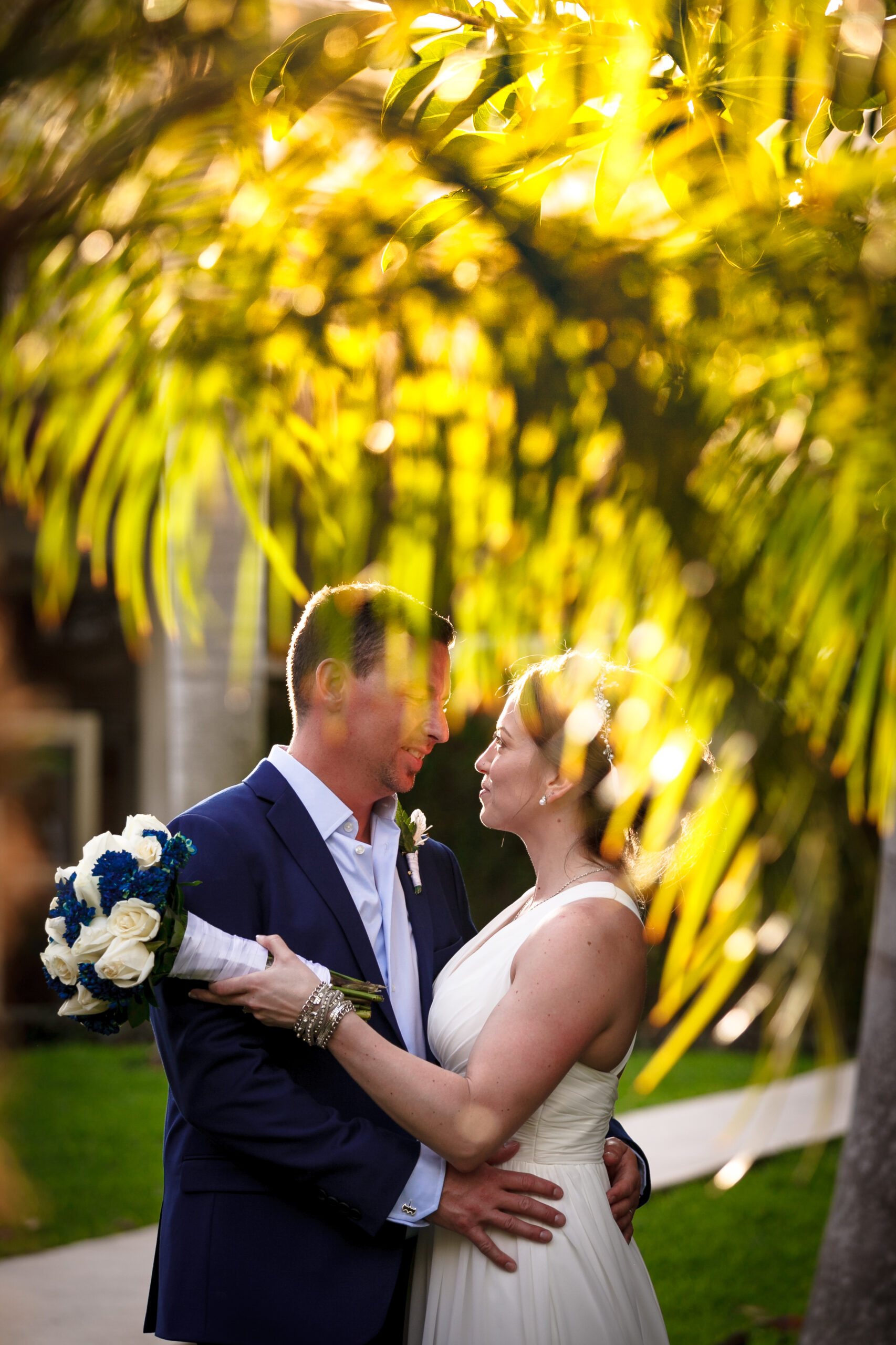 Newlyweds embrace under sunset palm tree