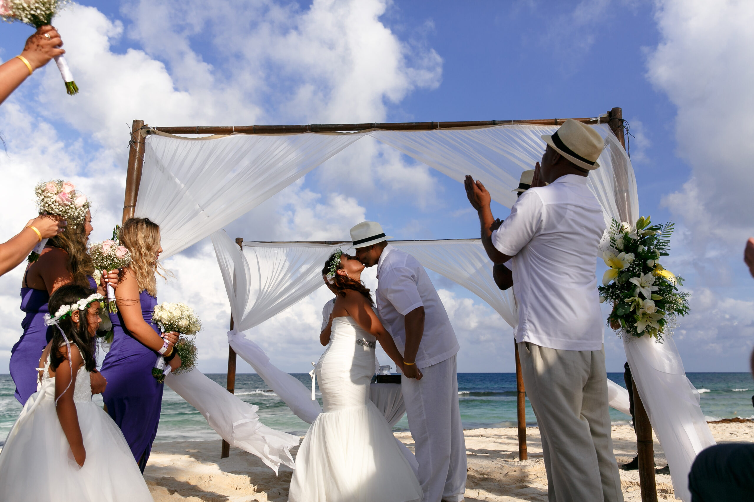 Guests applaud newlyweds' first kiss under beach pagoda at their destination wedding