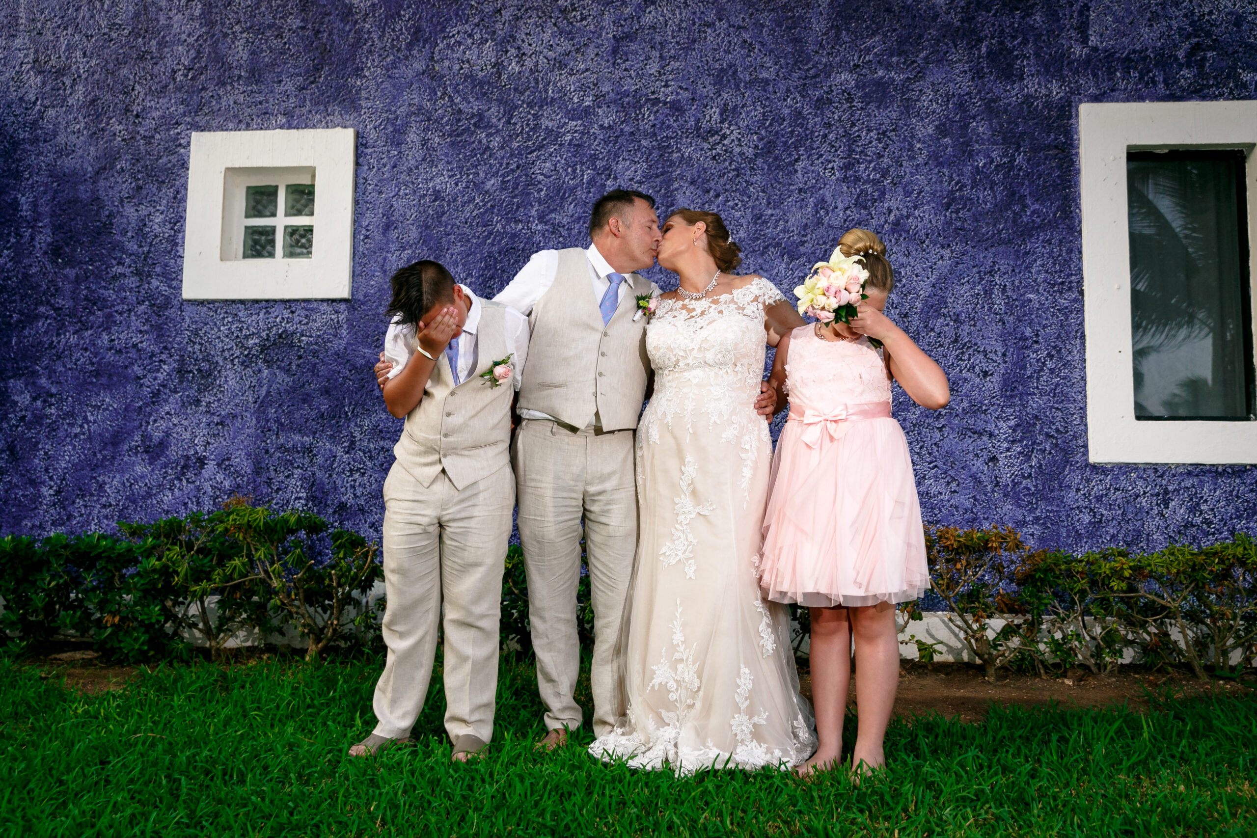 Kids grimace at their newlywed parents kissing