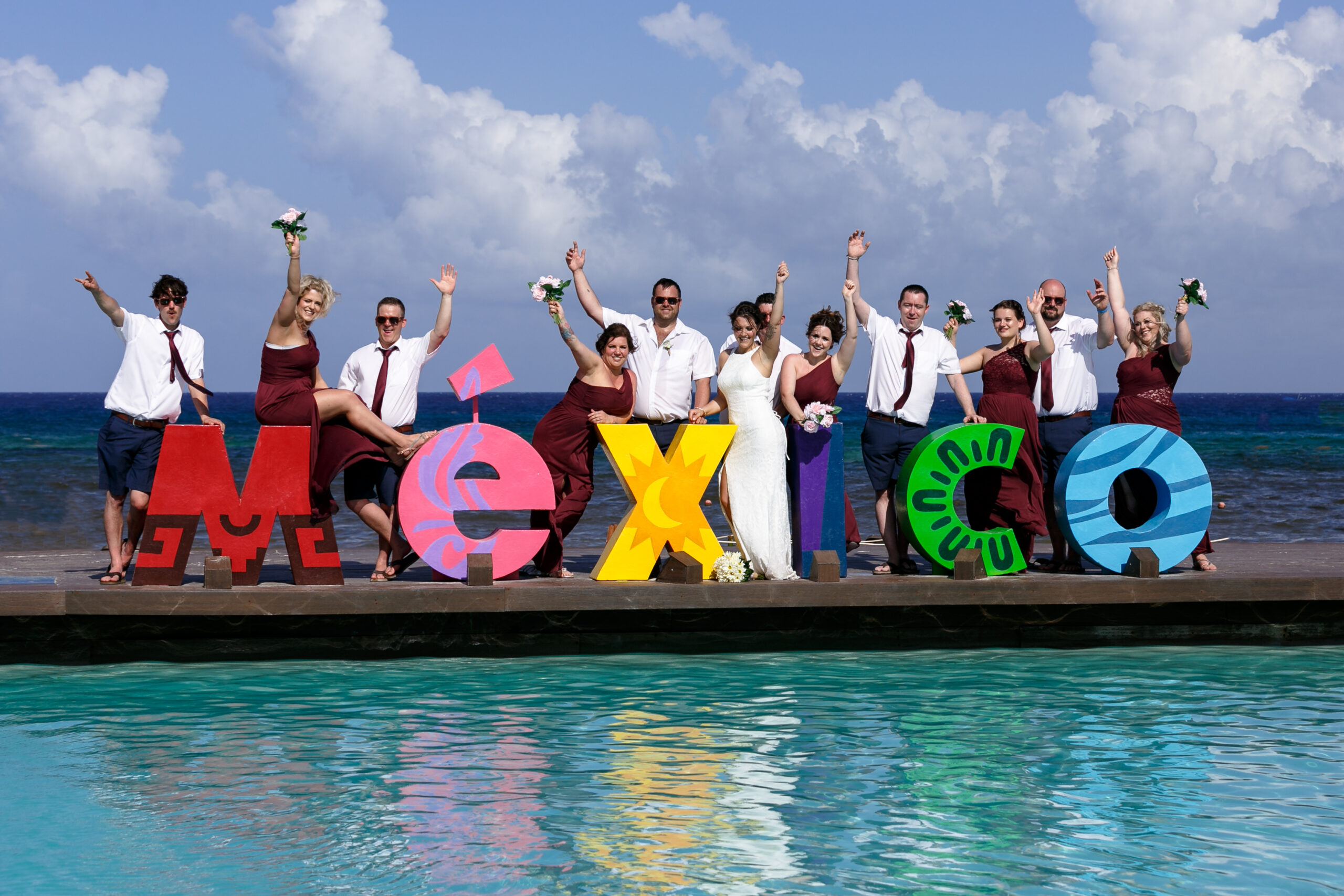 Wedding party cheer, posing on Mexico sign