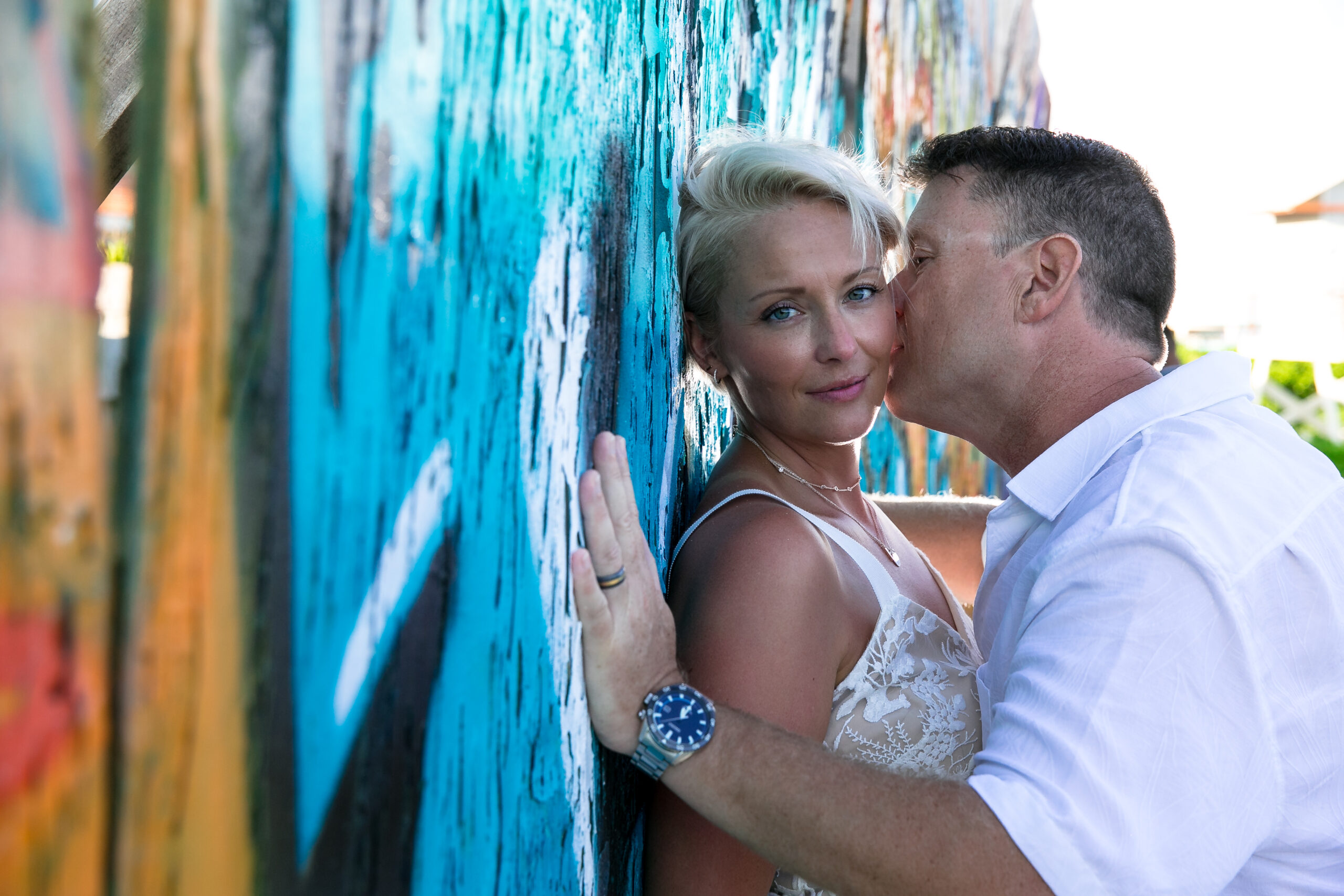 Anniversary couple kisses at graffiti wall