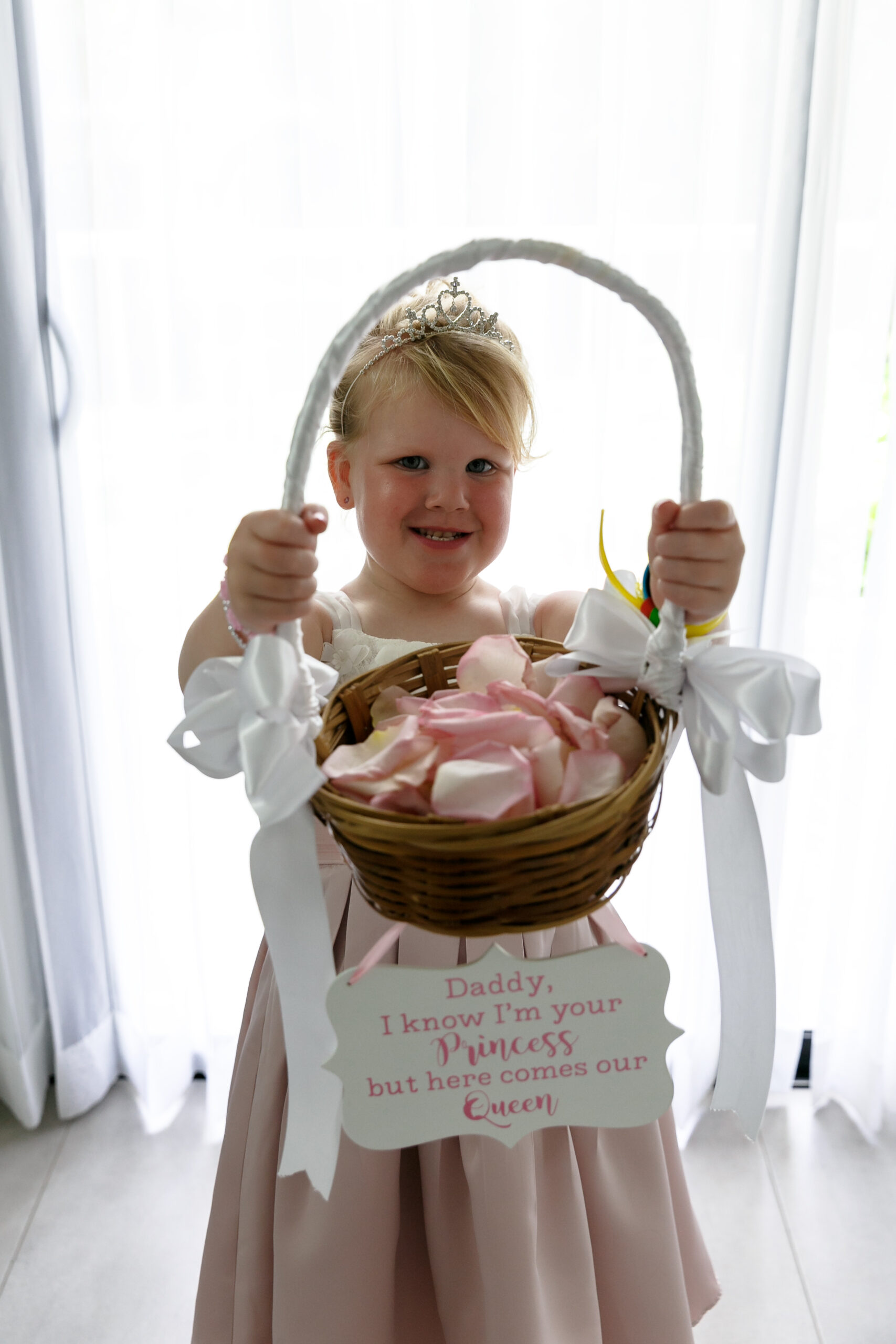 Adorable daughter holds basket and sign for her father, the groom