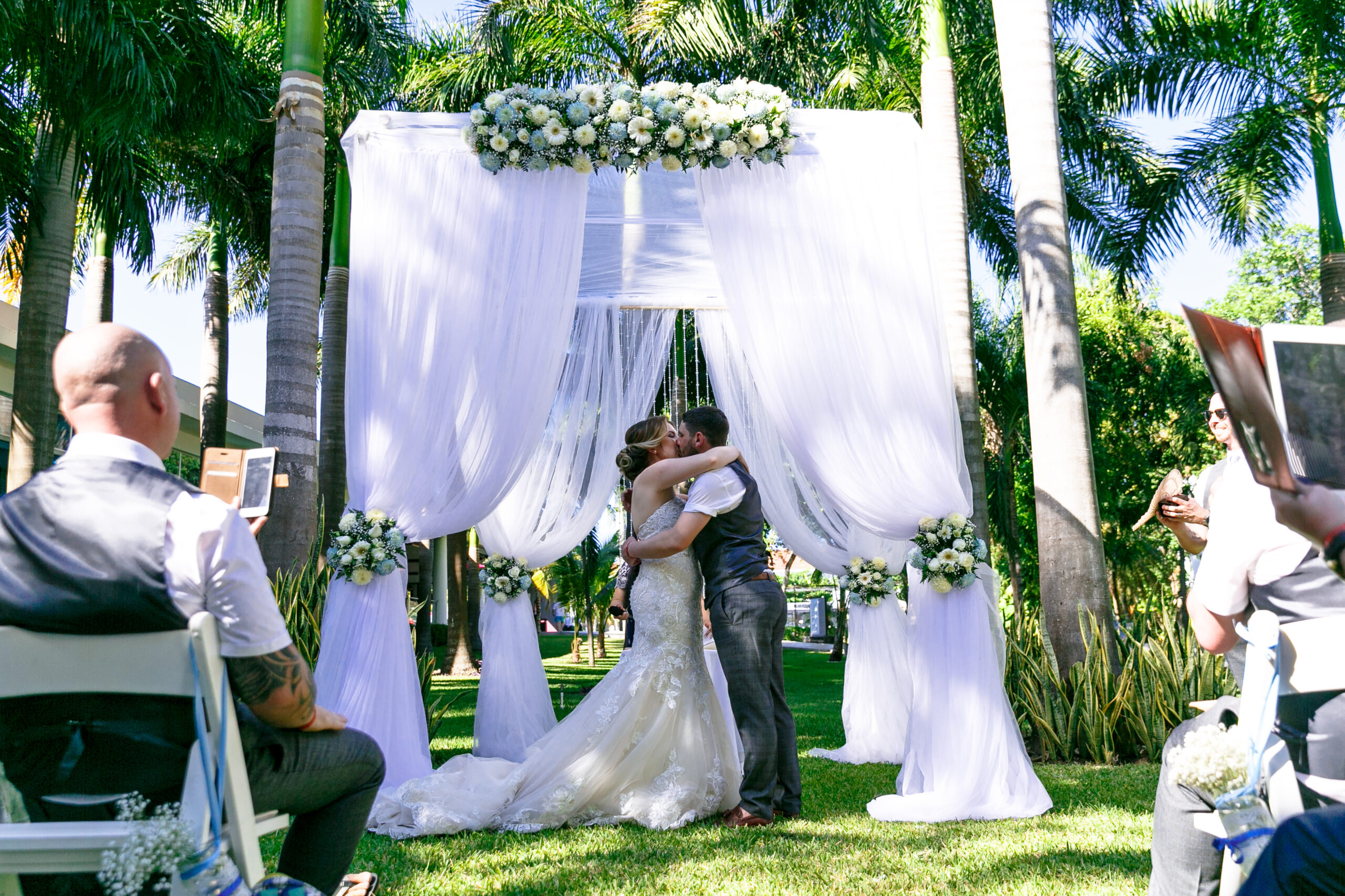 Newlywed's first kiss under billowy pergola nestled in the jungle