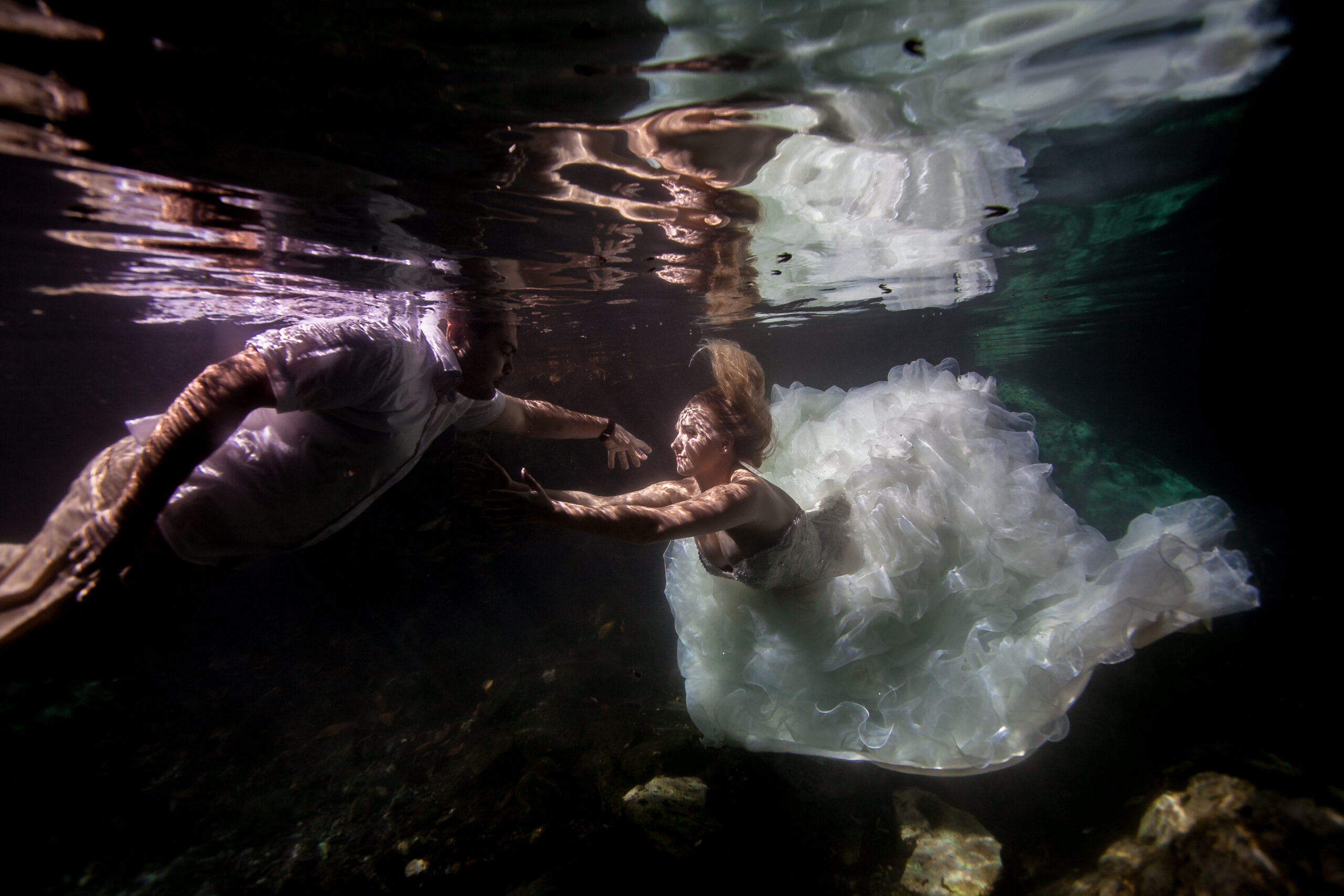 Underwater newlyweds reach for each other