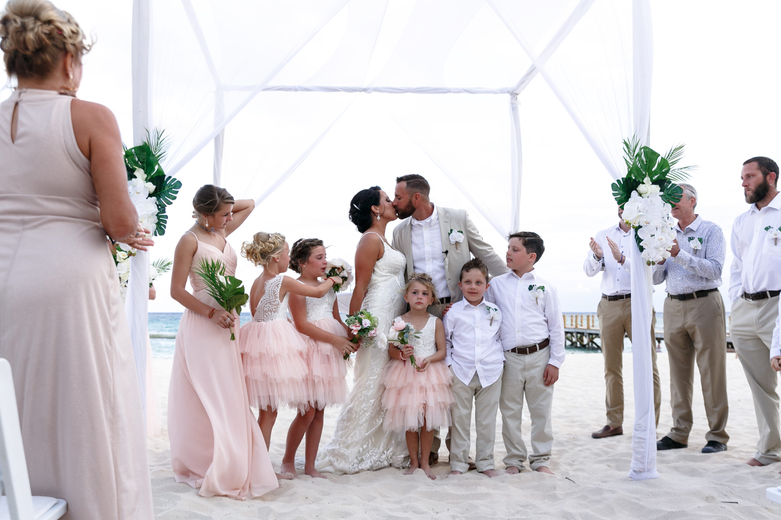 Bride and groom kiss, surrounded by their newly blended family