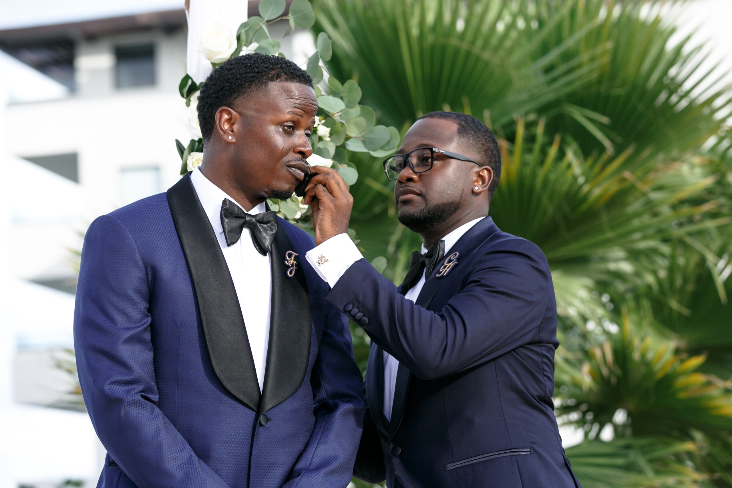 Groomsman wipes tears from emotional Groom's face as he watches his bride approach