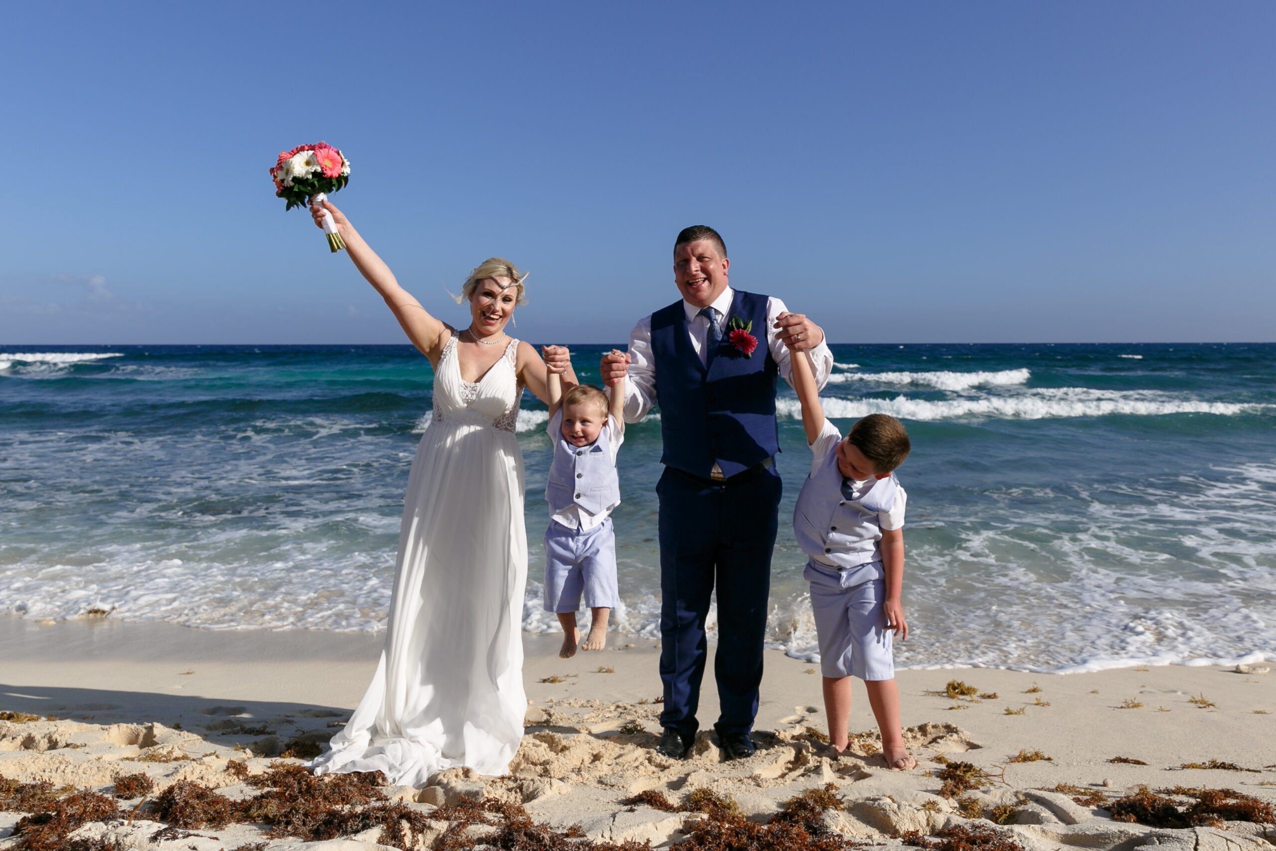 Newlyweds cheer on the beach with their two sons