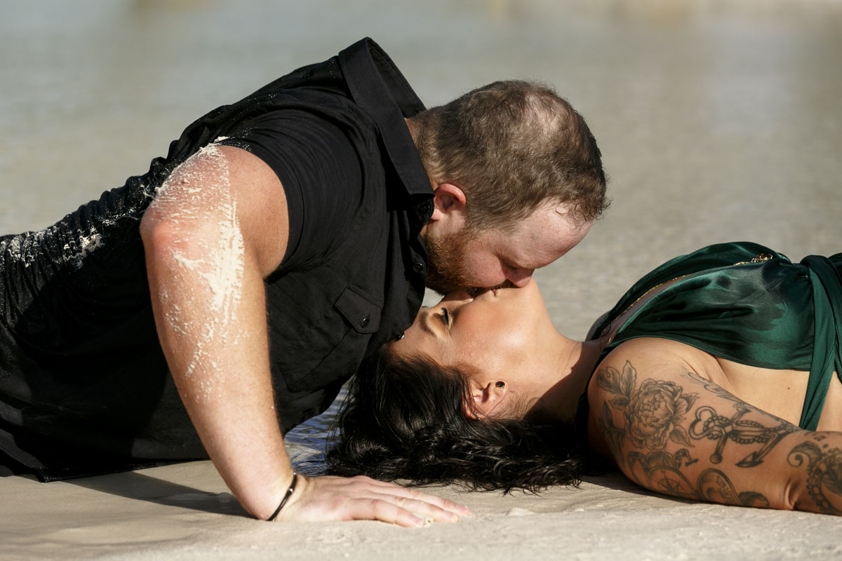 Anniversary couple kiss in the shallow beach water