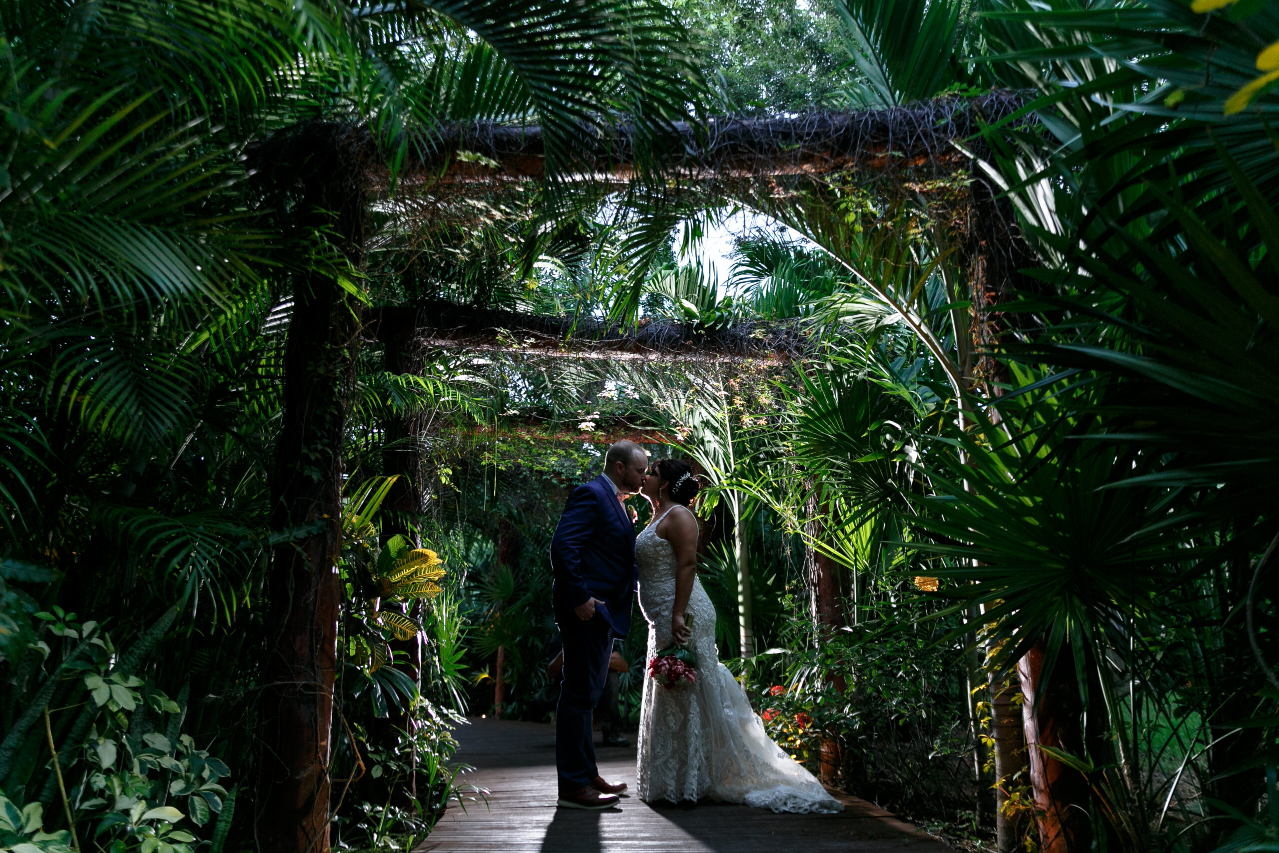 Newlyweds kiss under green jungle arches