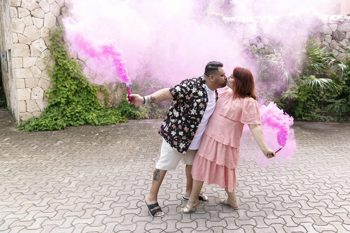 Newly engaged couple kiss amid billowing pink smoke