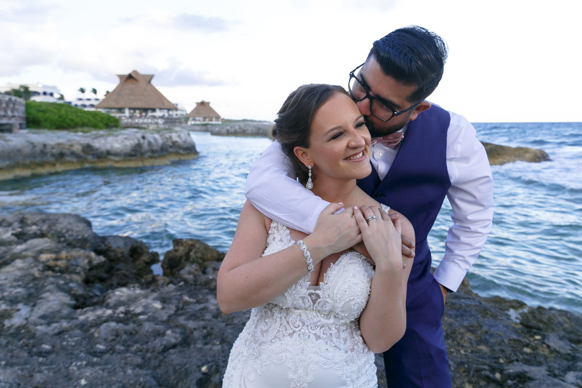 Newlywed groom kisses his bride beside the ocean