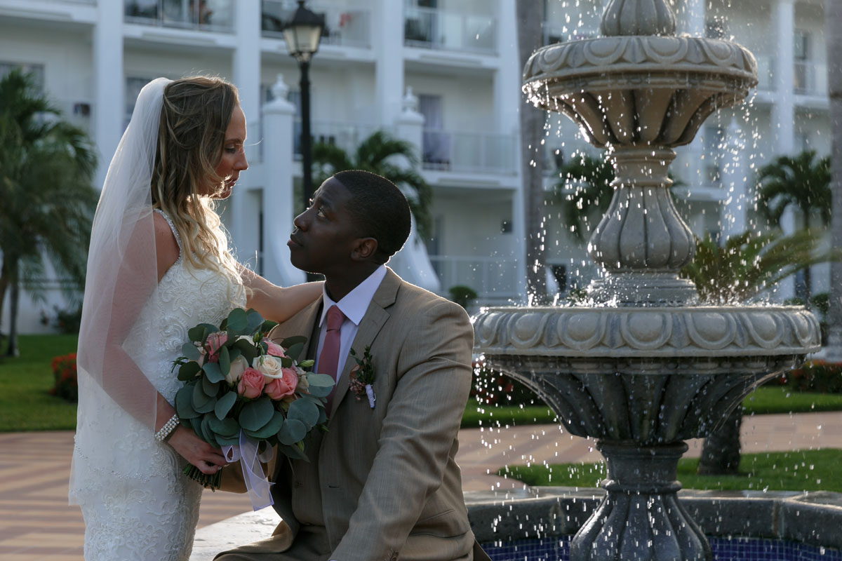 Newlyweds gaze intio each others' eyes next to fountain