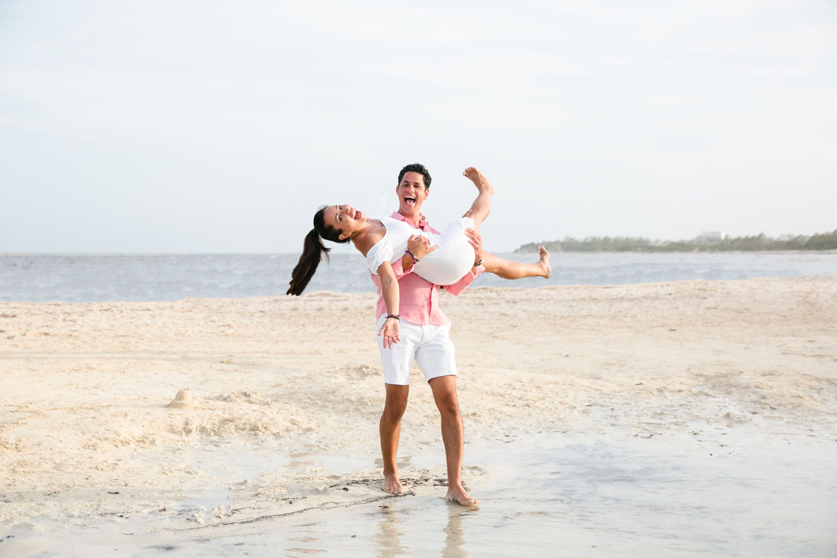 Husband swinging wife around on the beach