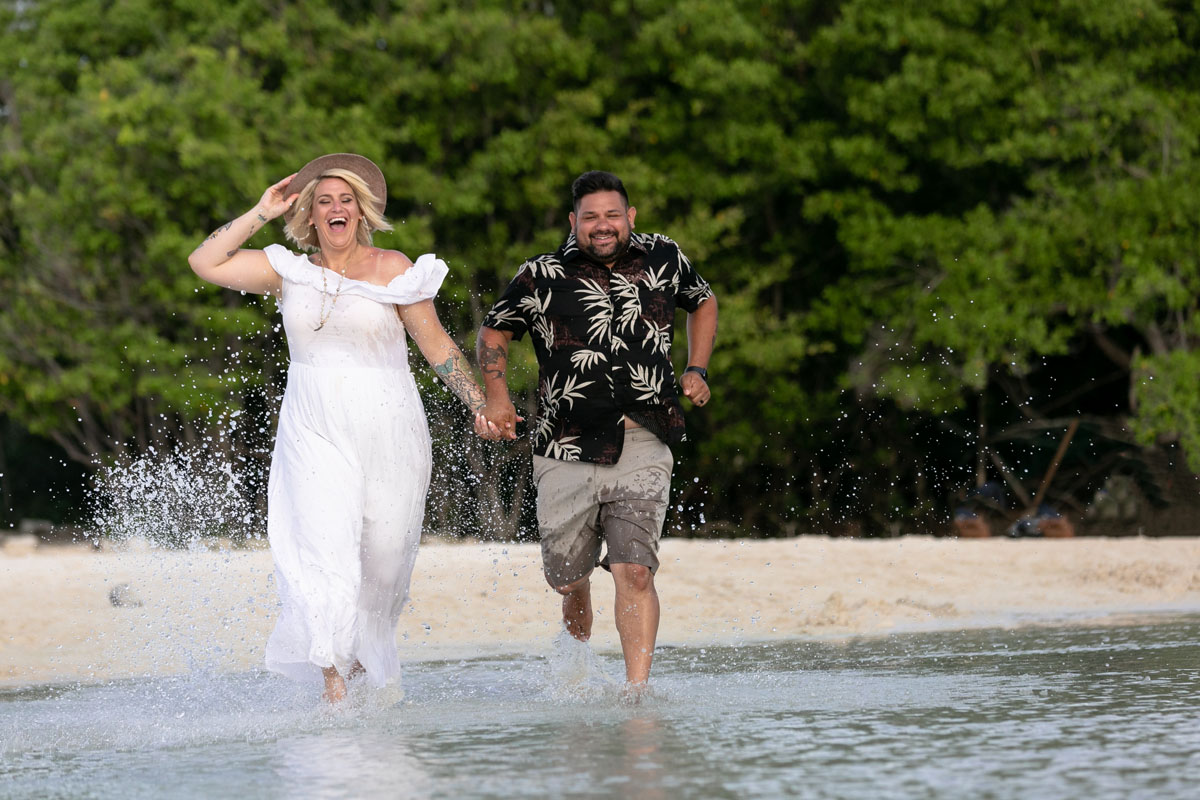 Playful couple splashing through the shallows at the beach