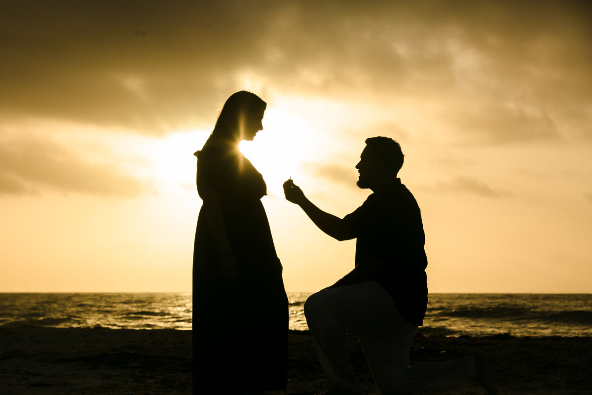 Boyfriend holds up engagement ring with his proposal of marriage