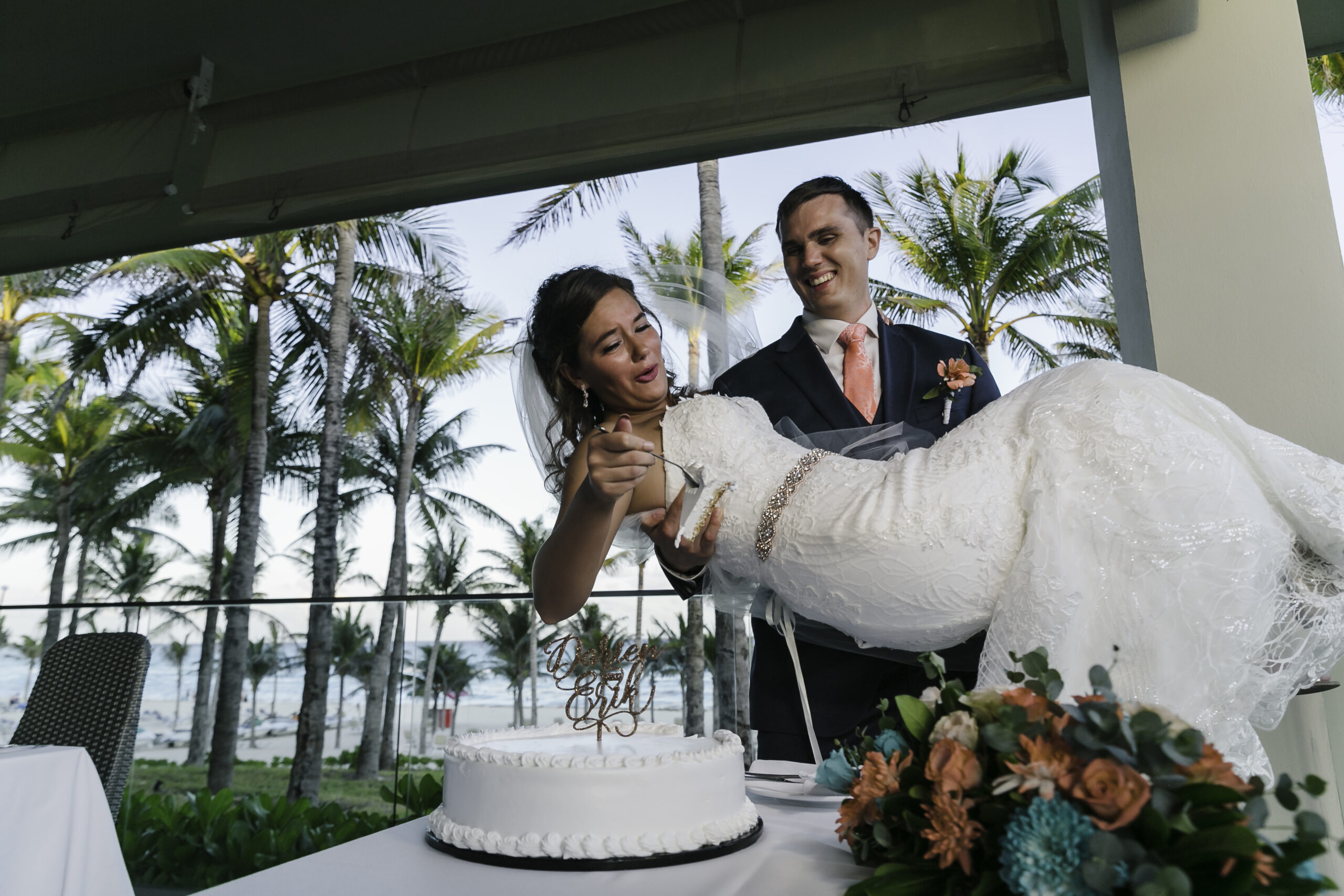 Husband lifts his bride as she scoops cake on a fork