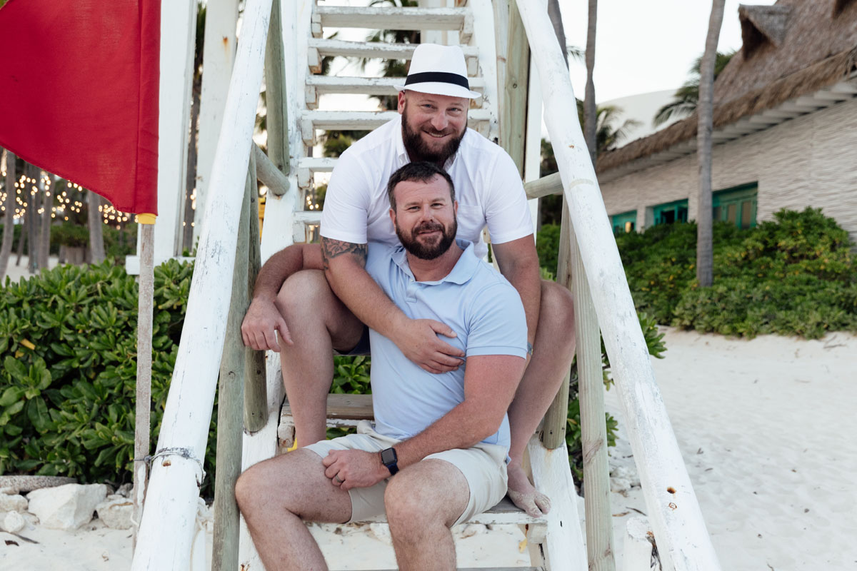 Gay couple sitting on steps of lifeguard tower on the beach