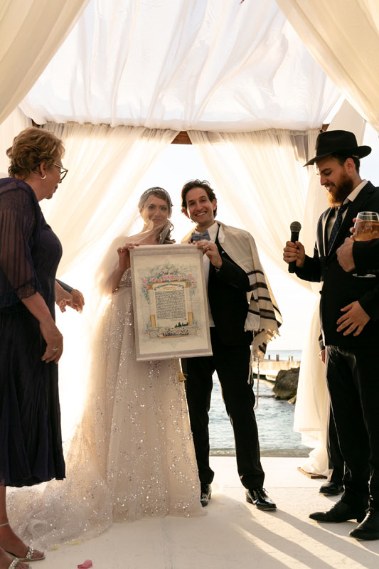 Wedding couple hold up their banner of promises at their Jewish ceremony