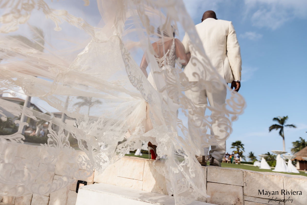 Brides lacy train floats up romantically as she walks with her groom