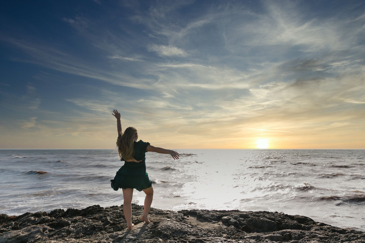 Senior salutes sunrise on Tulum beach