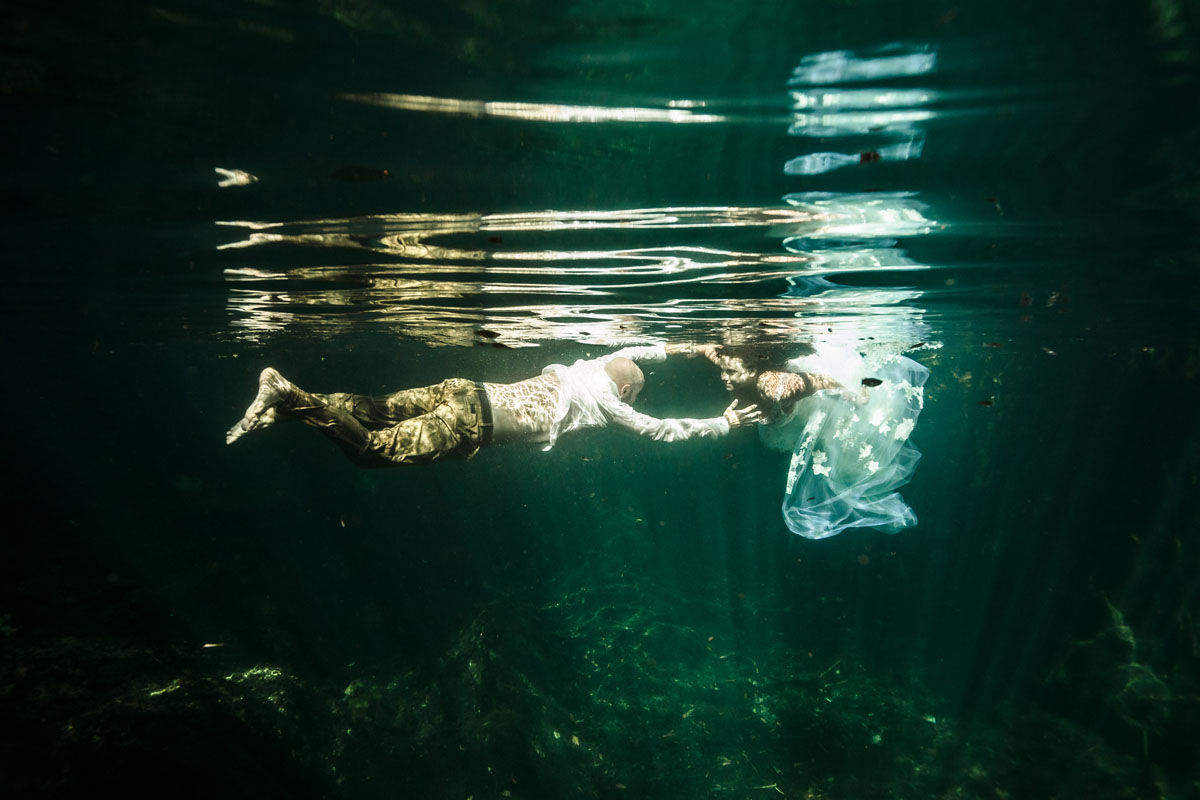 Newlyweds swim toward each other in crystal clear cenote