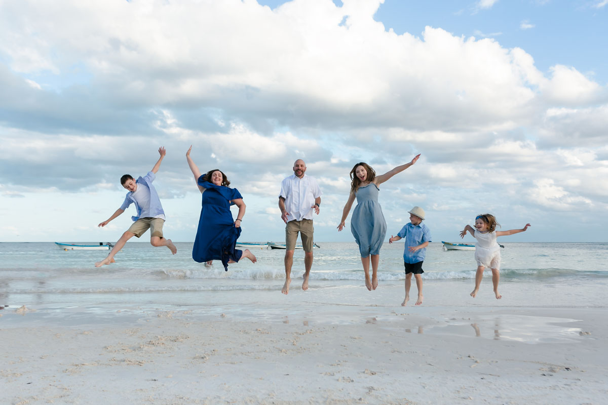 Happy family jump for joy on Tulum beach