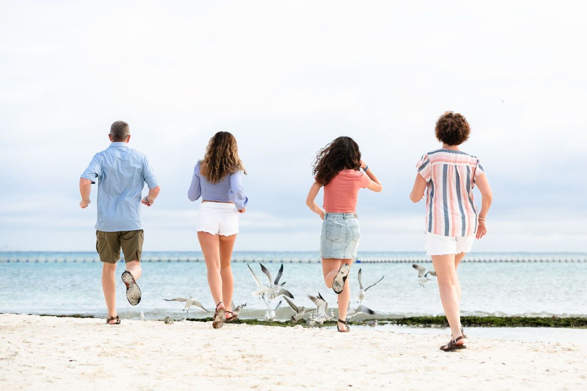 family chasing gulls at the beach