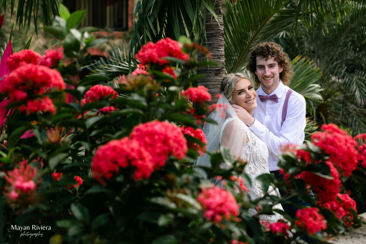 Newlyweds framed with scarlet tropical flowers
