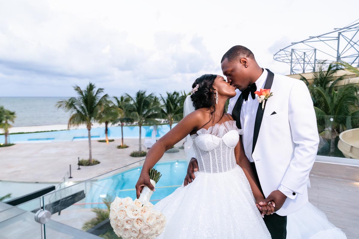 Newlyweds kiss on rooftop terrace overlooking azure ocean