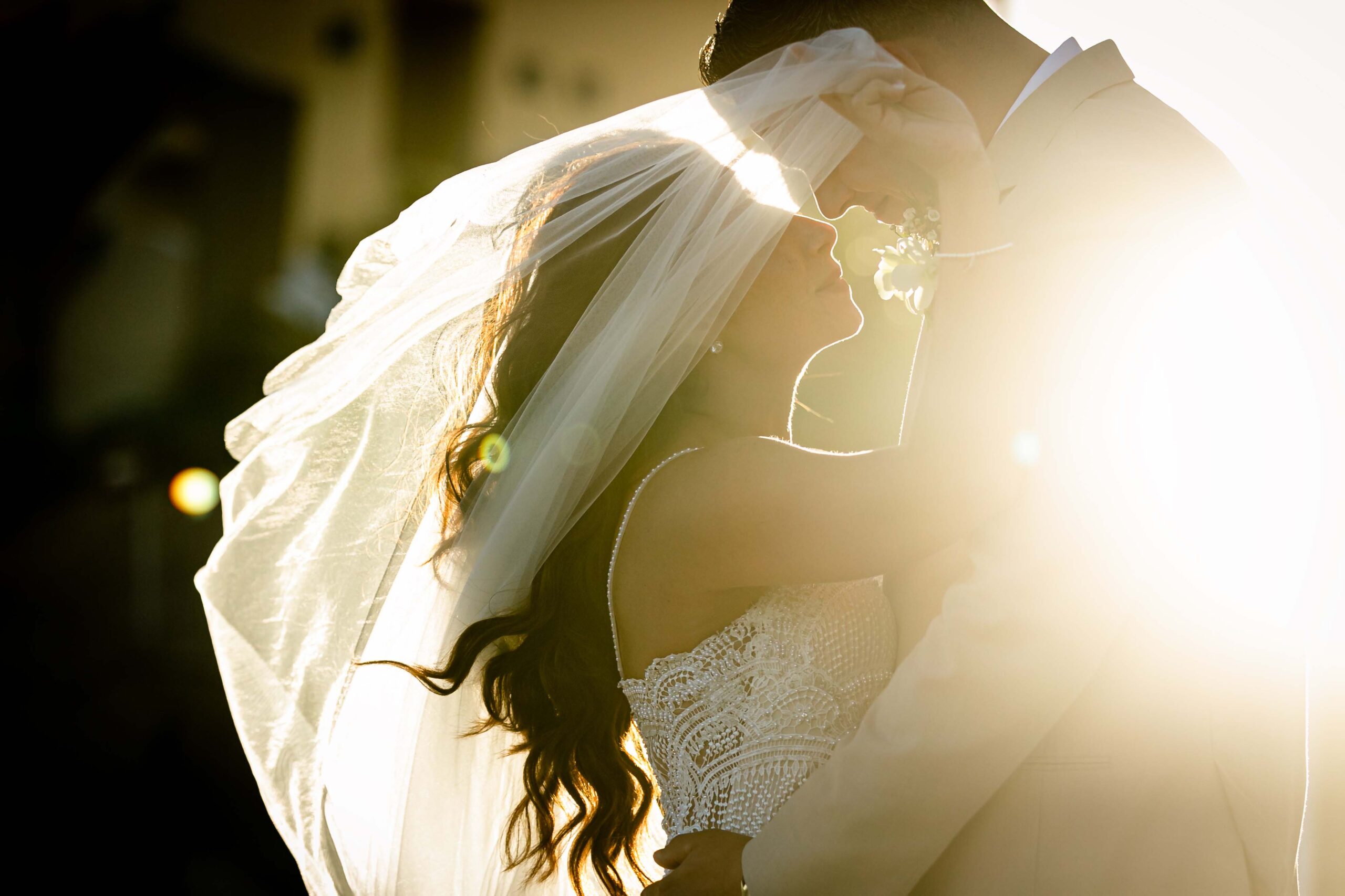 newlyweds kiss under billowing veil at sunset