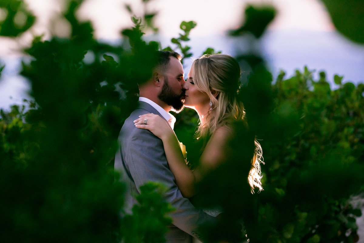 Newlyweds kiss in jungle silhouetted in sunlight