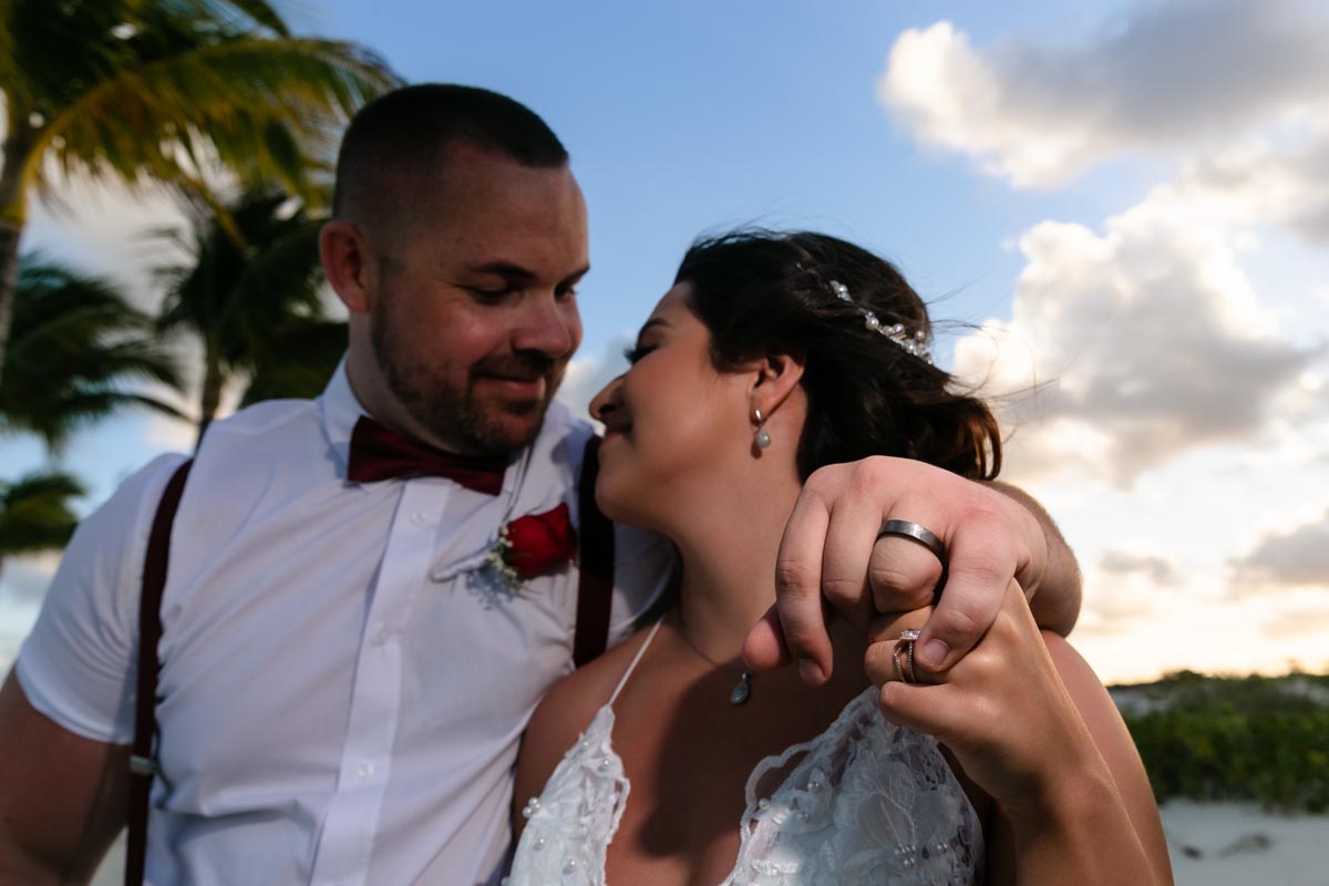Newlyweds show their rings in a beach embrace