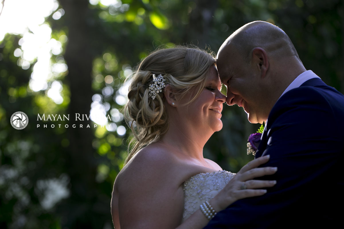 Newlyweds embrace under sunlit palm frond