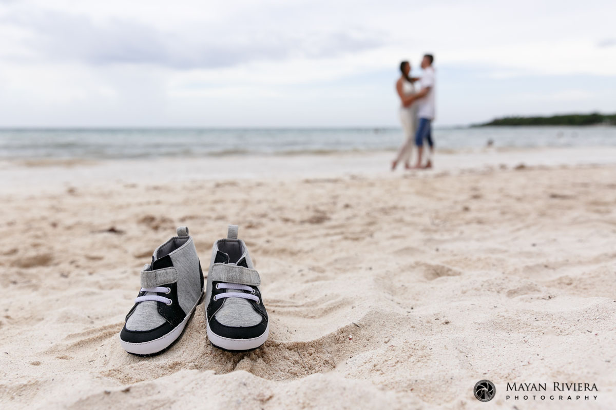 ExpectantParentsPoseOnBeachWithBabyShoes