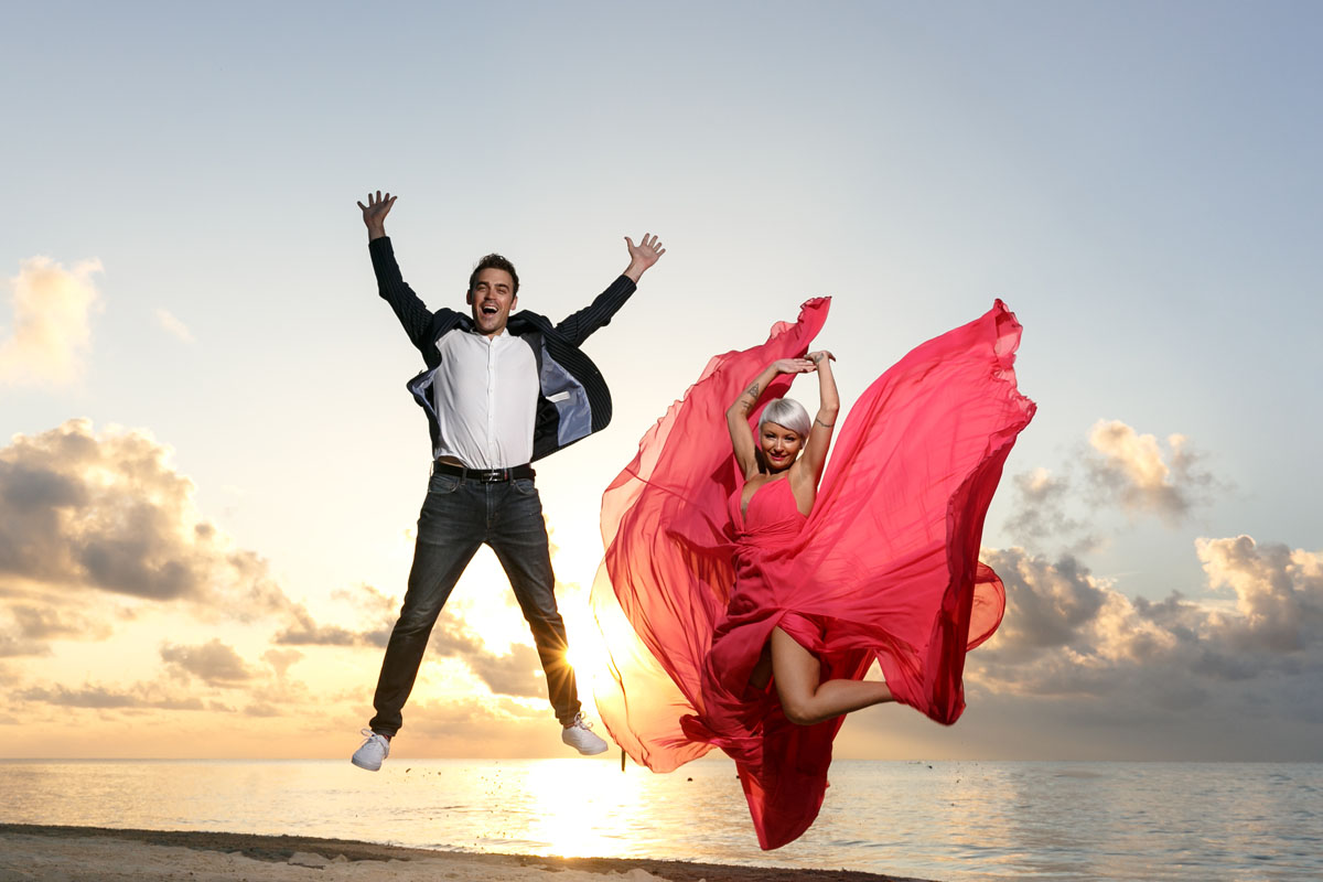 CoupleJumpForJoyOnBeachAtSunrise