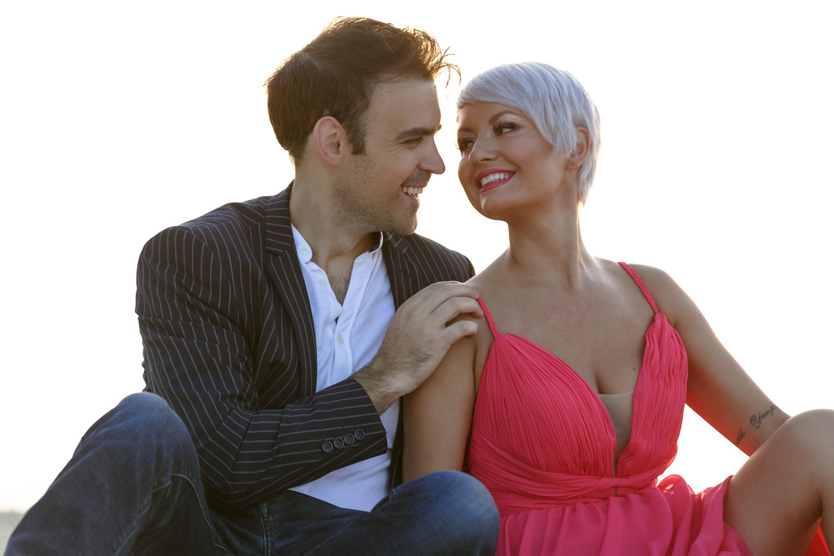 CoupleSmileAtEachOtherOnBeachAtSunrise
