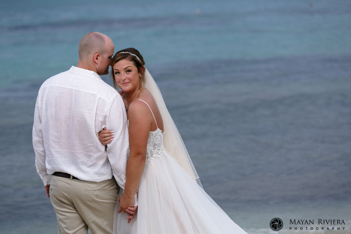 SmilingBrideHoldsGroomsArmOnBeach