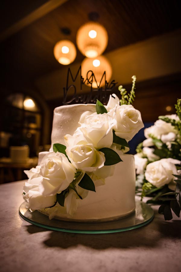 Gorgeous white tower wedding cake decorated with white roses and an elaborate name topper