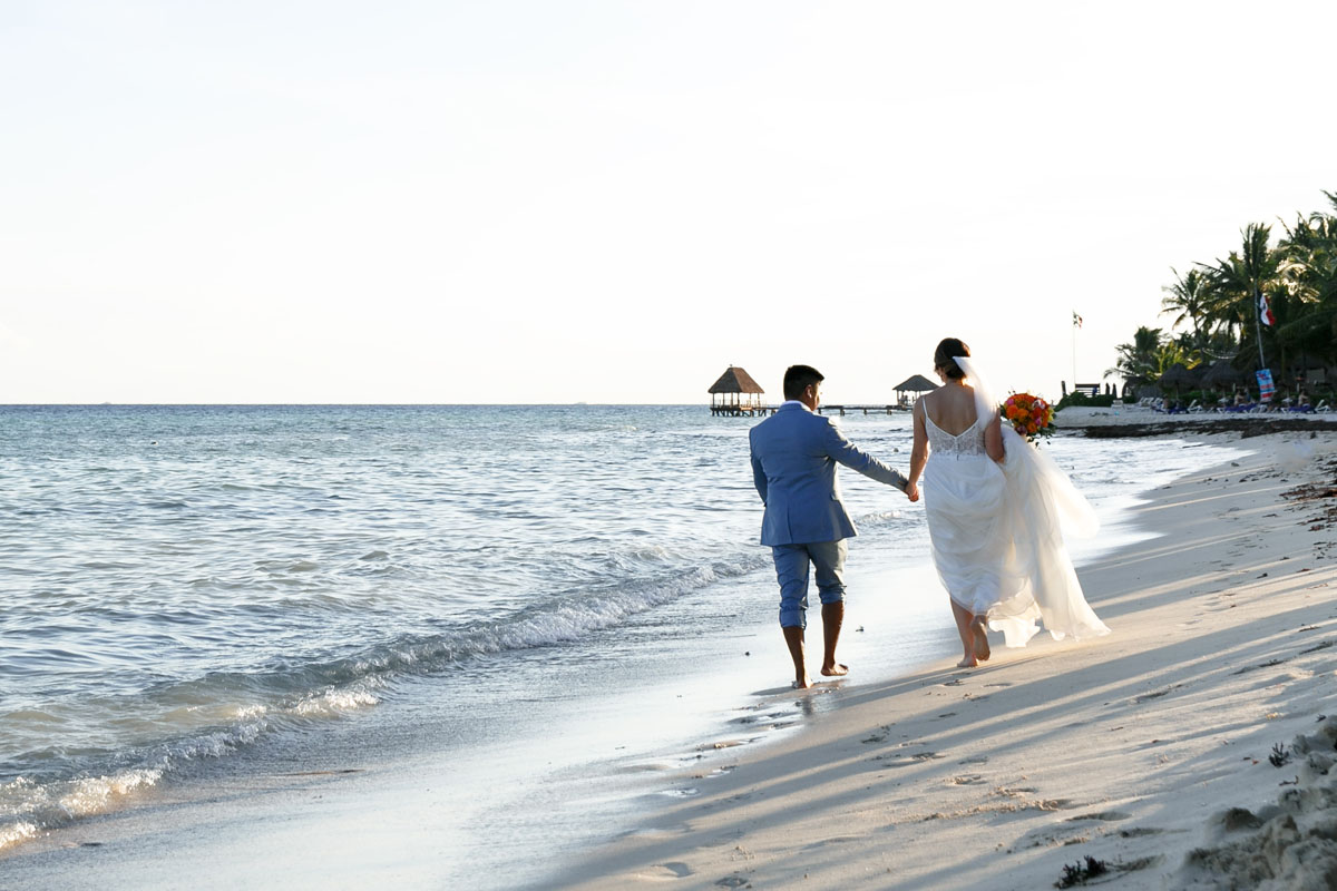 NewlywedsWalkBeachHoldingHands