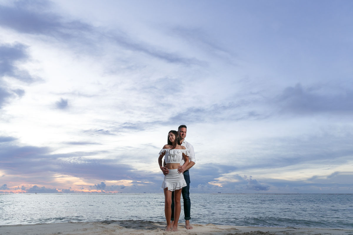 NewlyEngagedCouplePoseOnPdCBeachAtSunrise