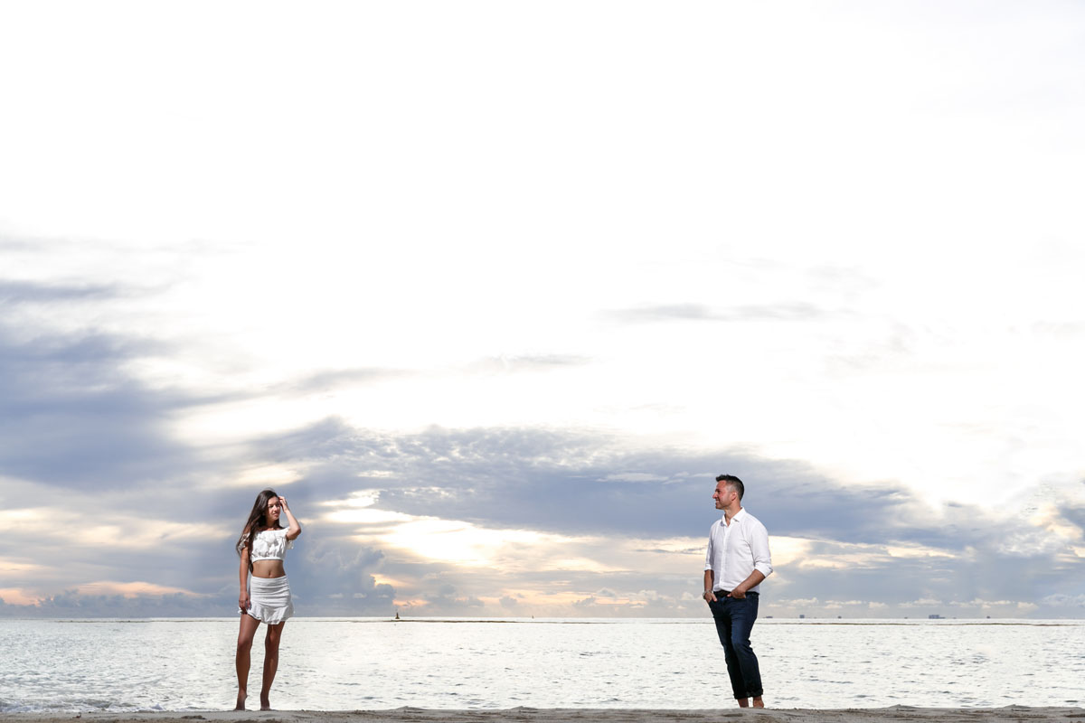 NewlyEngagedCouplePoseOnPdCBeachAtSunrise
