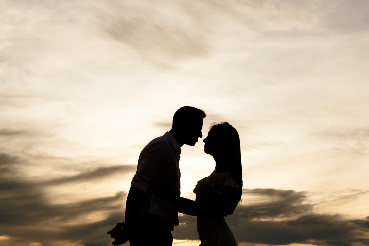 NewlyEngagedCouplePoseOnPdCBeachAtSunrise