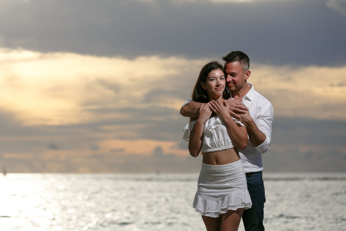 NewlyEngagedCouplePoseOnPdCBeachAtSunrise