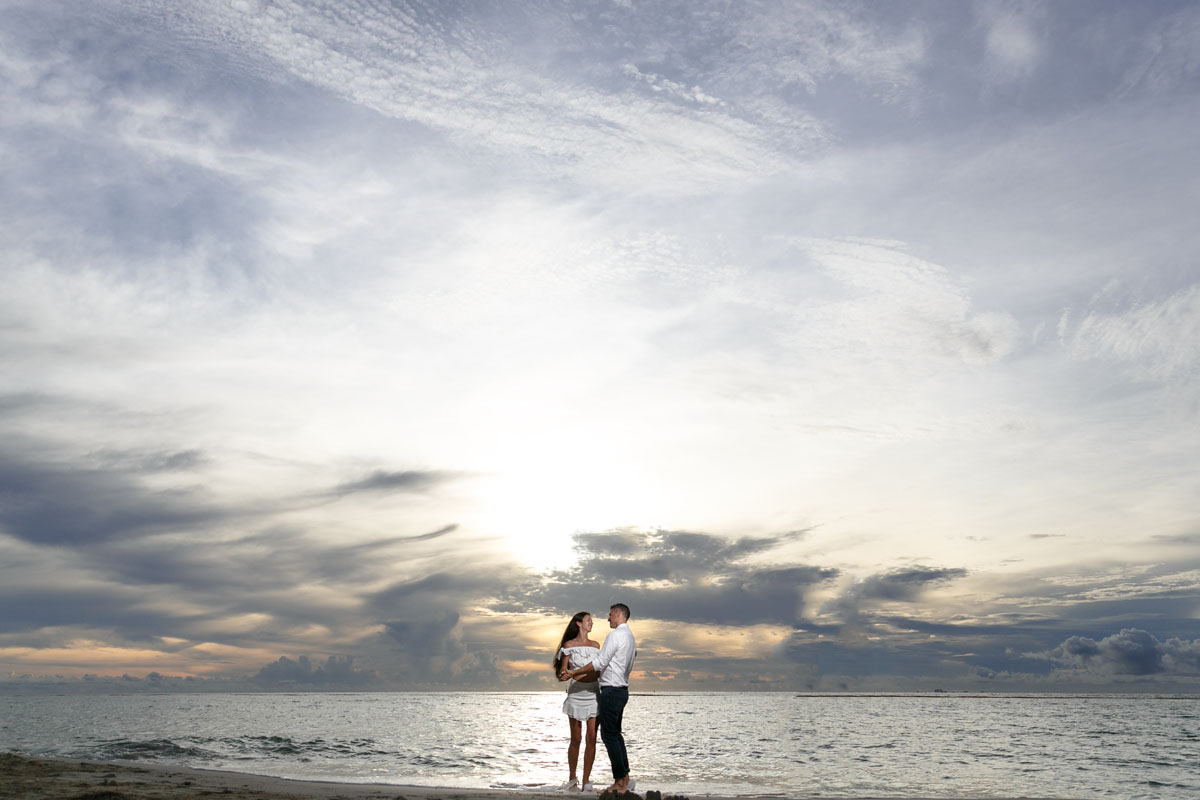 NewlyEngagedCouplePoseOnPdCBeachAtSunrise