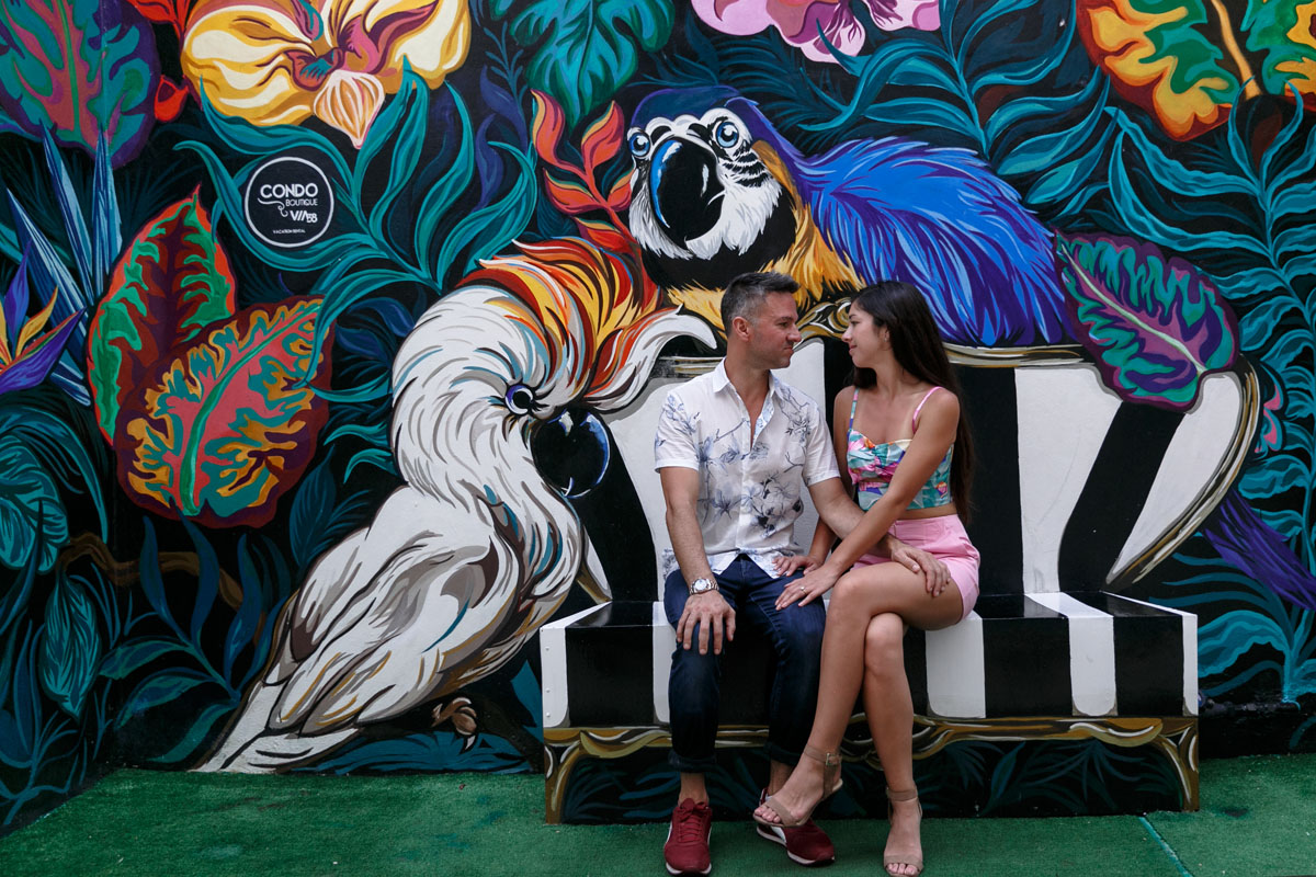 NewlyEngagedCoupleSitOnBenchByGraffitiWall