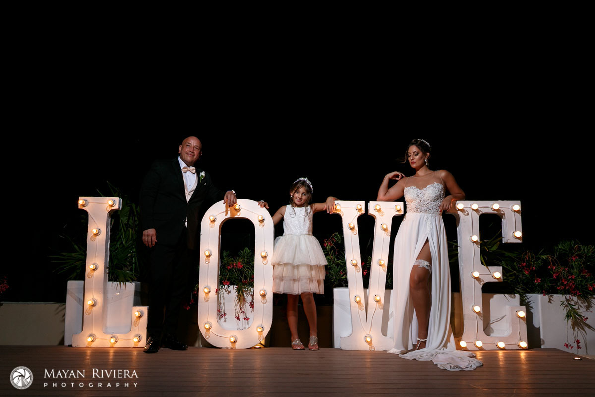 NewlywedsPoseInLoveSignWithFlowerGirl