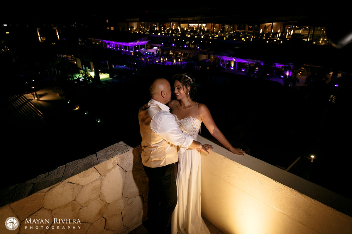 NewlywedsInEachOthersArmsOnRooftopBalcony
