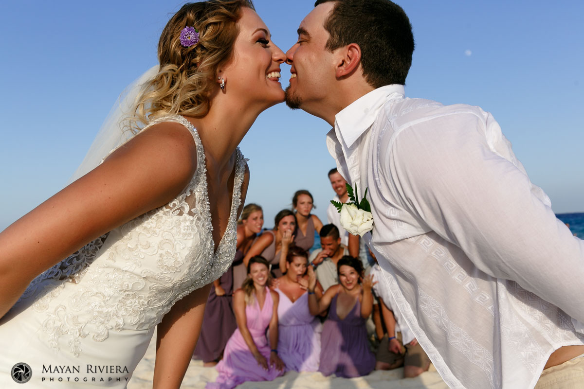 GigglingNewlywedsFrameWeddingPartyOnBeach